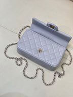 Light blue Chanel flap bag with quilted pattern, gold-tone clasp, and chain shoulder strap.