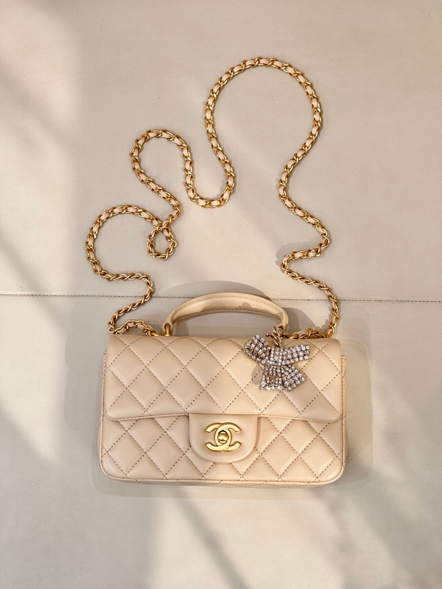 Chanel quilted leather bag with chain strap, top handle, and logo flap in light beige