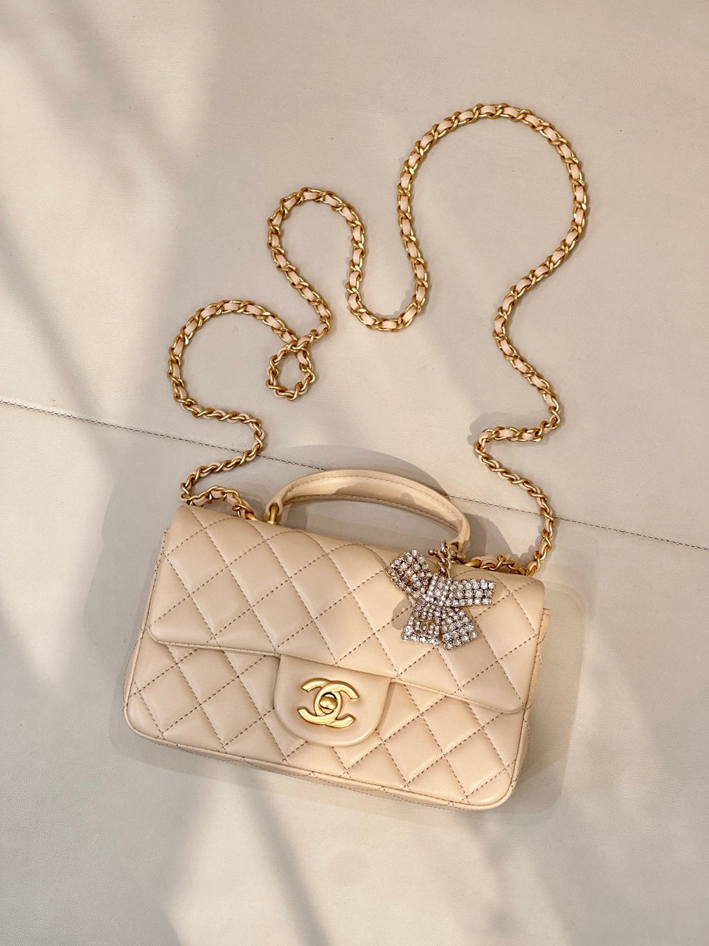 Chanel quilted bag with chain strap, top handle, logo flap, and crystal bow charm