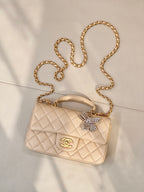 Chanel quilted bag with chain strap, top handle, logo flap, and crystal bow charm