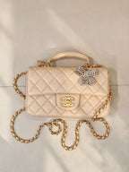 Chanel quilted leather bag with chain strap, top handle, logo flap, and crystal bow