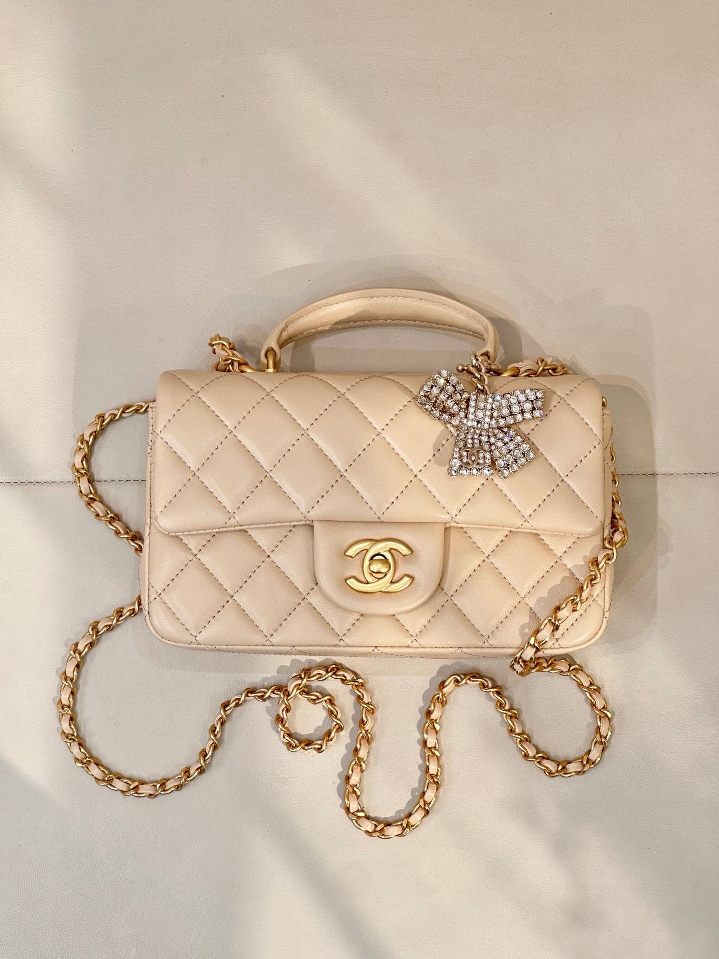 Chanel quilted leather bag with chain strap, top handle, logo flap, and crystal bow