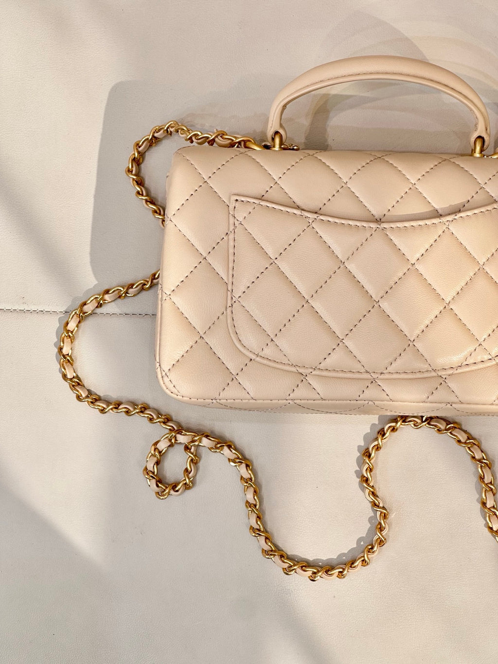 Chanel quilted leather bag close-up with logo flap and gold chain strap in light beige