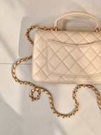 Chanel quilted leather bag close-up with logo flap and gold chain strap in light beige