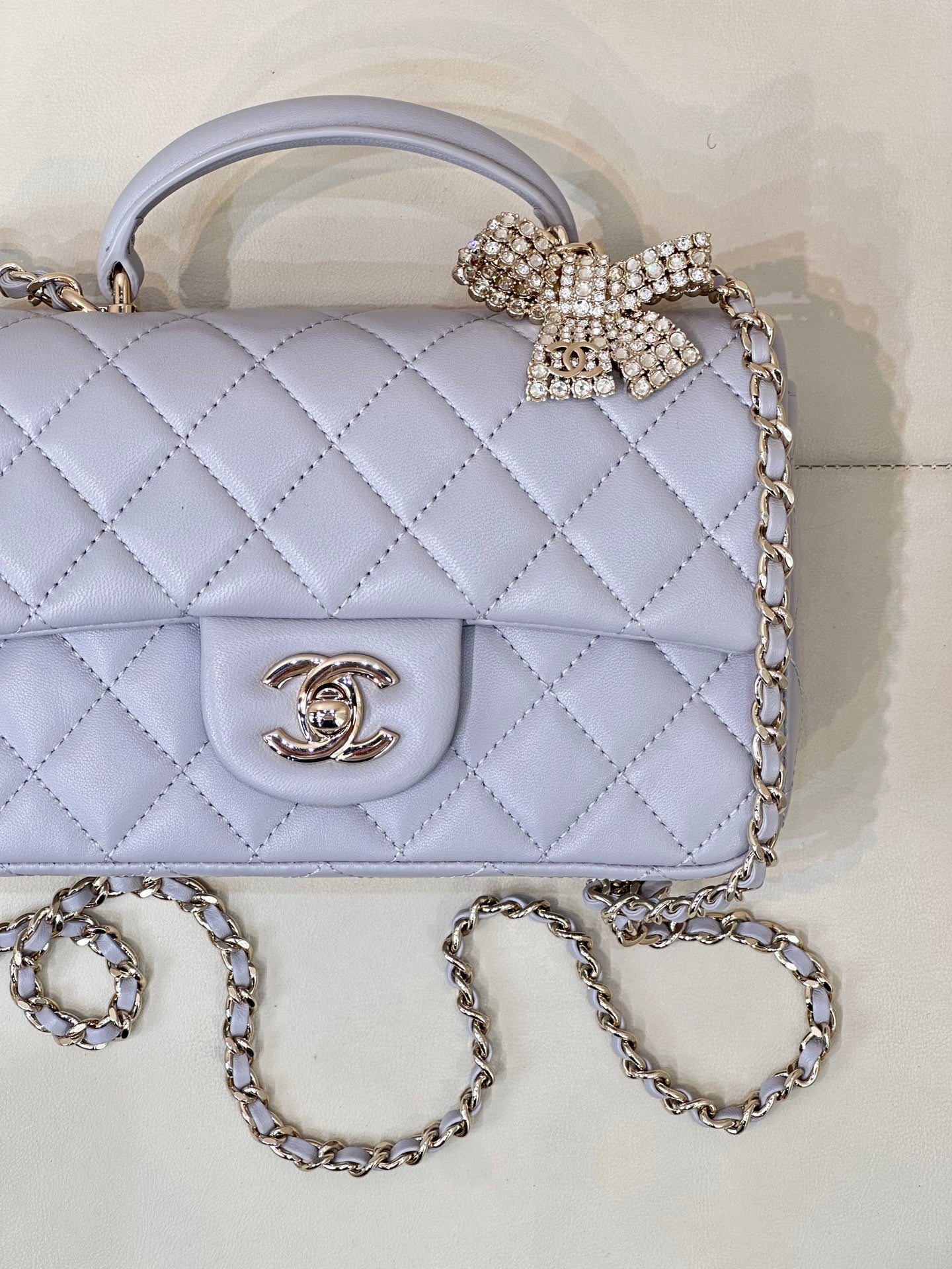 Quilted Chanel flap bag in light blue with gold CC logo and rhinestone bow detail.