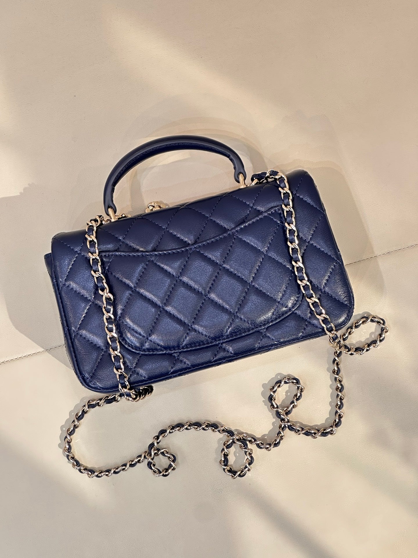 Quilted blue flap handbag with chain strap and top handle, stitched diamond pattern