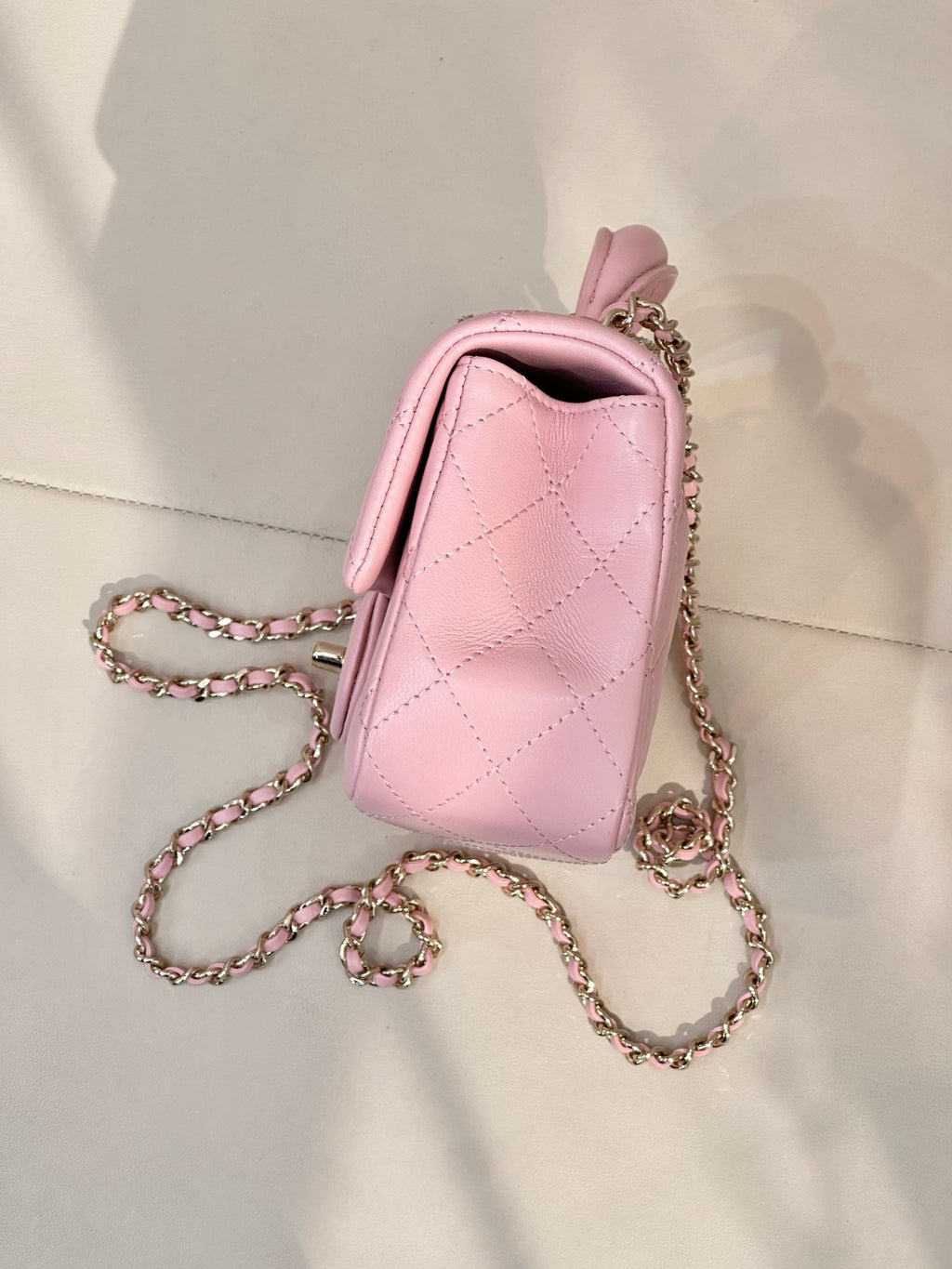 Chanel pink quilted flap crossbody bag with short handle, chain strap, and side view