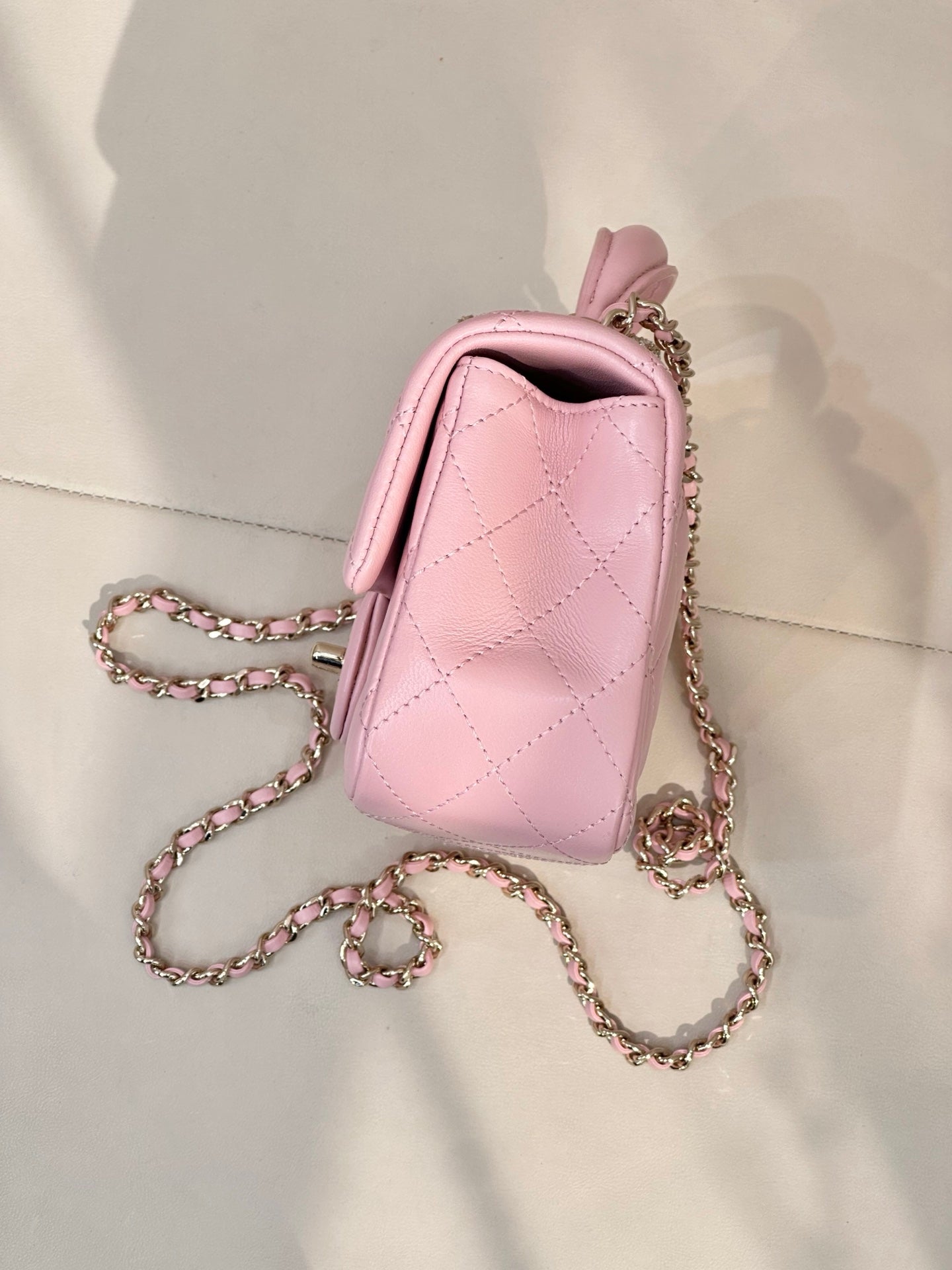 Chanel pink quilted flap crossbody bag with short handle, chain strap, and side view
