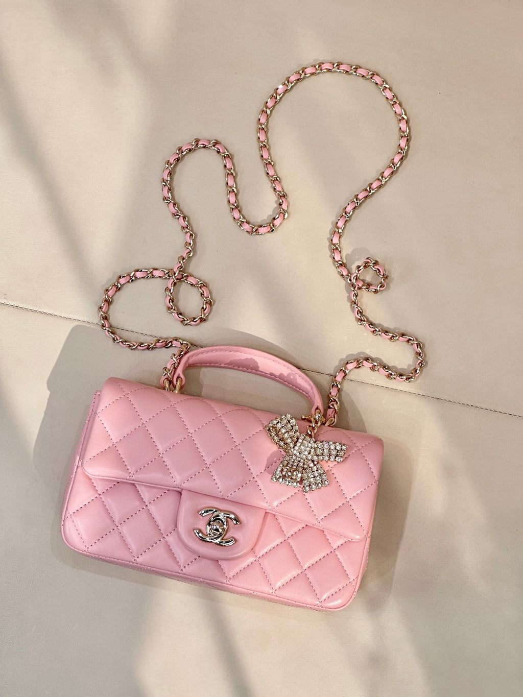 Chanel quilted pink flap bag with bow embellishment, chain strap, and metal CC logo