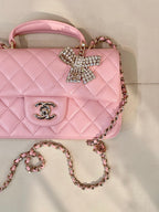 Chanel pink quilted flap bag detail with rhinestone bow, CC emblem, and chain strap