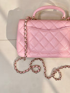 Chanel pink quilted flap bag close-up with CC logo, chain strap, and handle top view