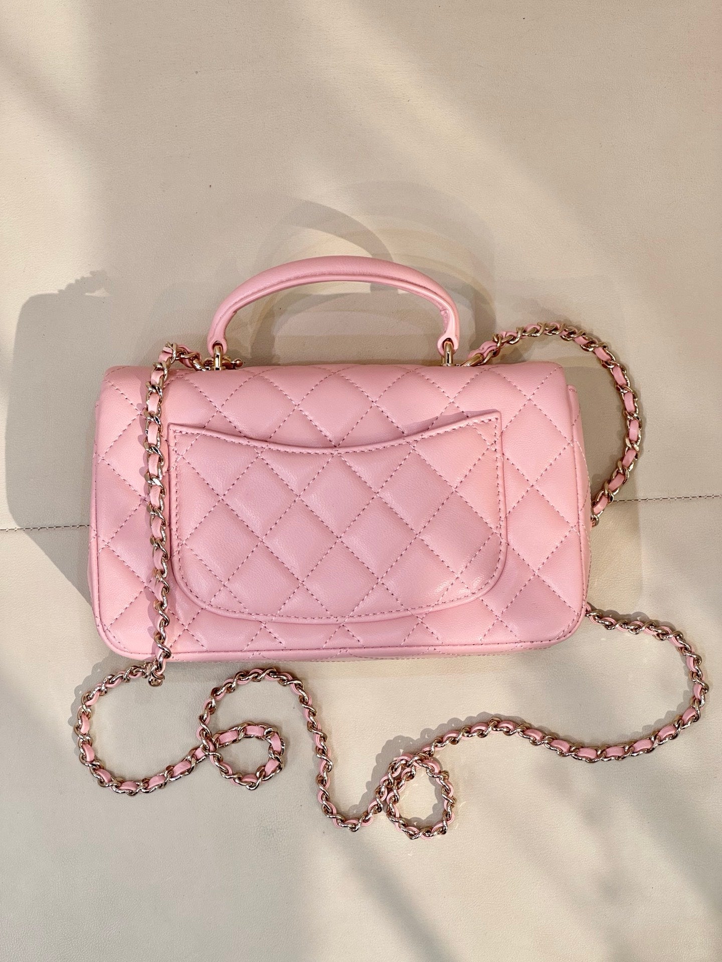 Chanel pink quilted flap bag with short handle, chain strap, and curved front detail