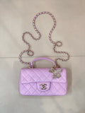 Quilted light purple handbag with gold-tone clasp and chain shoulder strap, bow charm