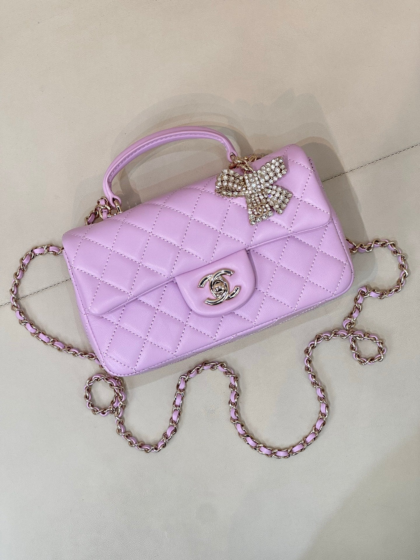Quilted light purple mini handbag with curved top handle, front logo, and chain strap