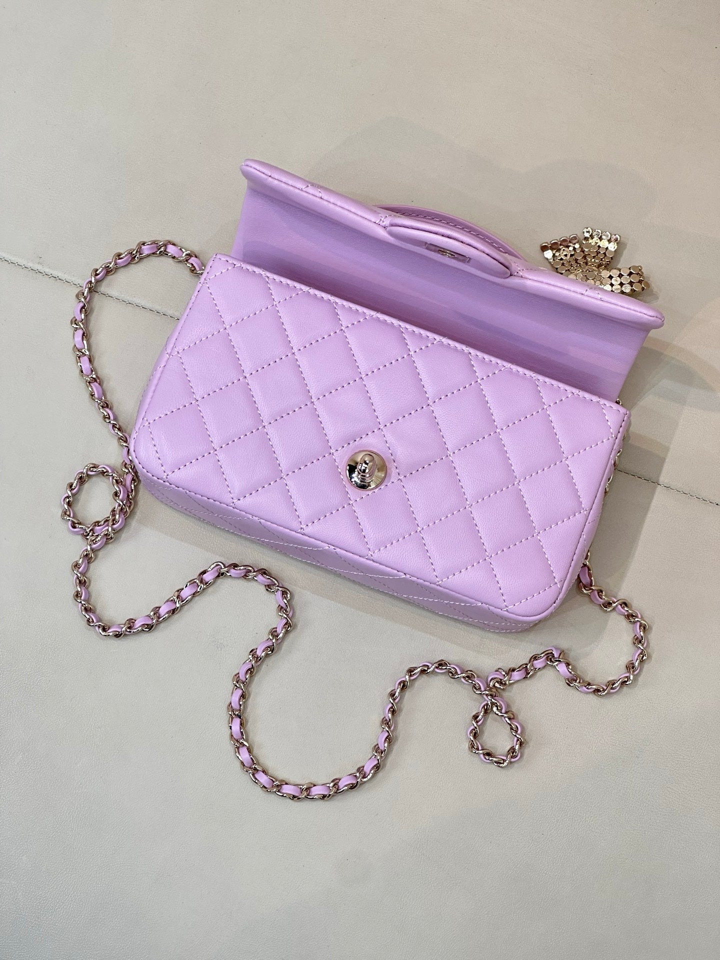 Quilted light purple handbag side view with open interior and chain shoulder strap