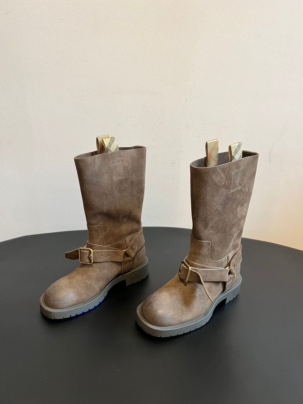Pair of suede ankle boots with buckled straps and chunky lug rubber soles.
