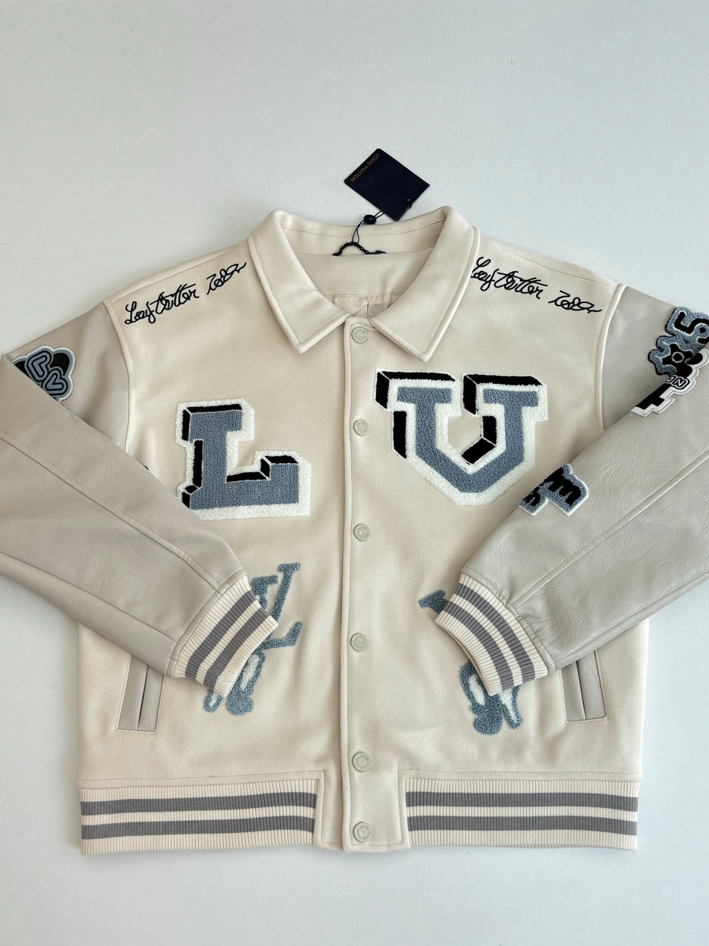 Louis Vuitton cream long-sleeve jacket with blue logo patches and ribbed knit cuffs