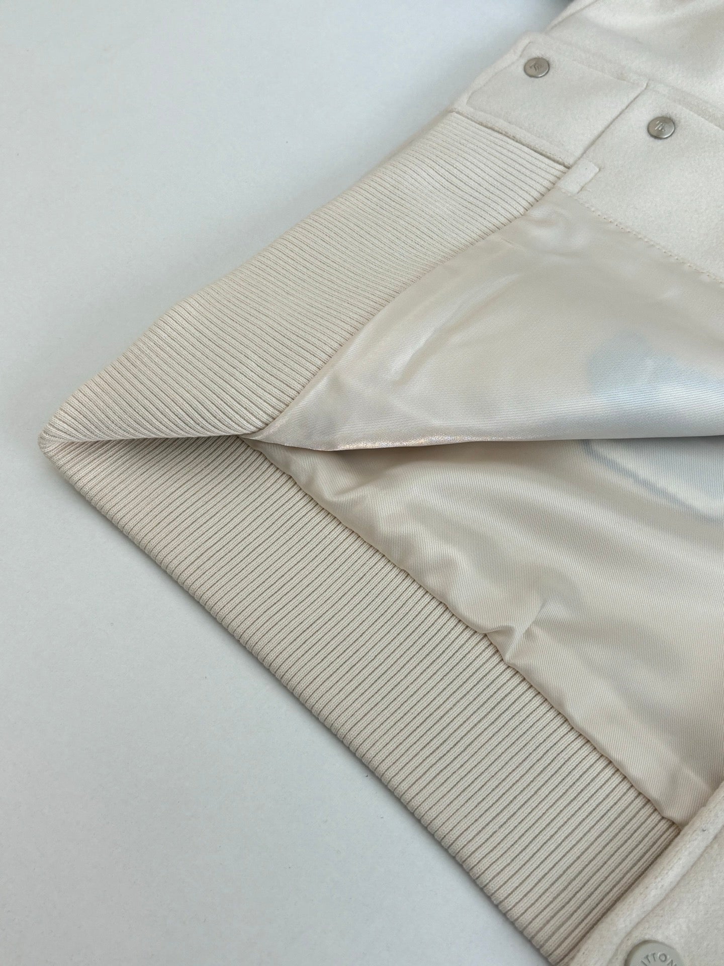 Louis Vuitton cream jacket sleeve with ribbed cuff and snap button placket details
