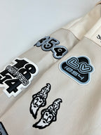 Cream long-sleeve jacket with patch graphics and ribbed sleeve cuffs