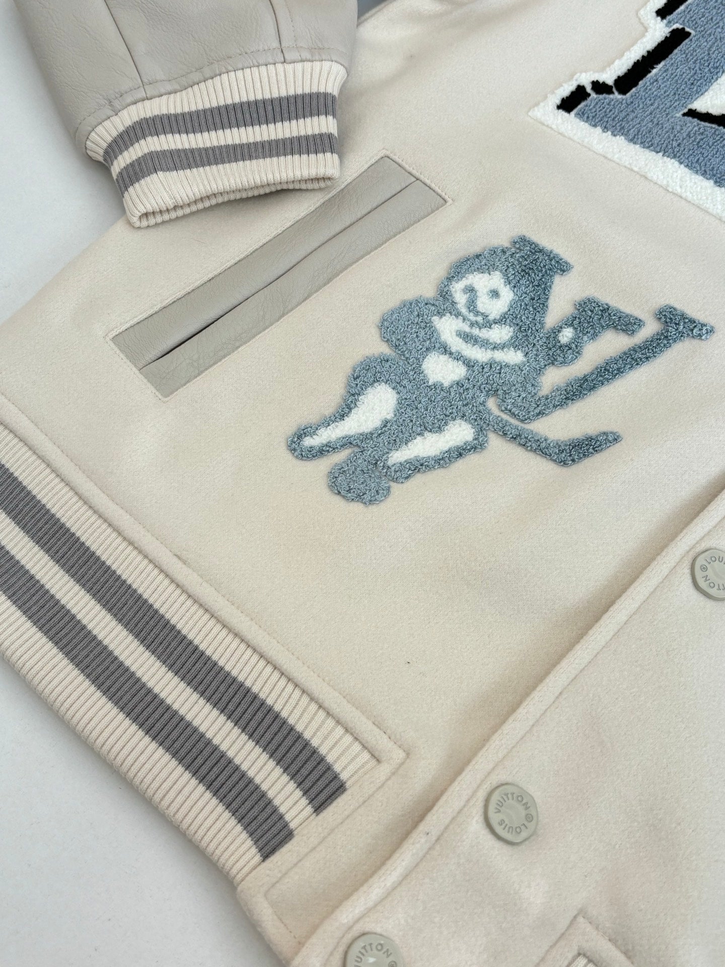 Louis Vuitton cream jacket hem with striped rib trim and blue cartoon patch