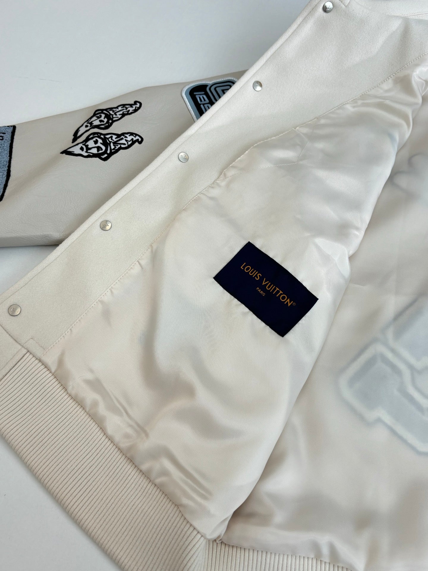 Cream long-sleeve jacket with snap-button placket and Louis Vuitton tag