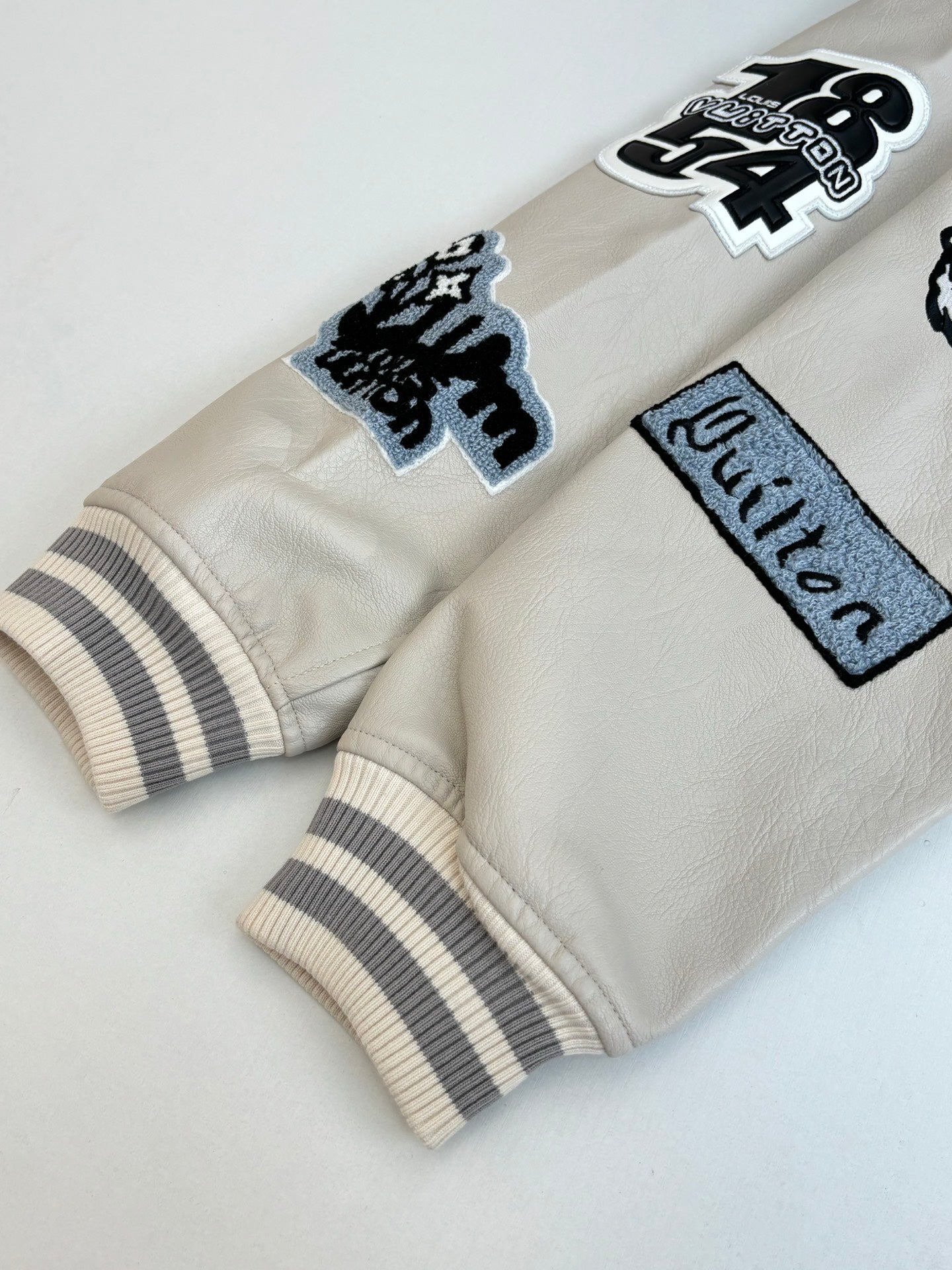 Cream long-sleeve jacket with patch graphics and striped ribbed cuffs