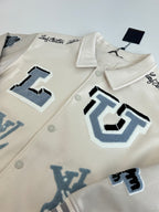 Louis Vuitton cream jacket close-up with blue applique graphics and snap buttons