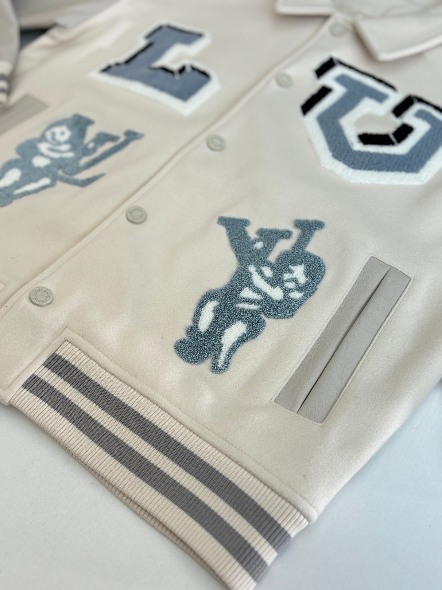 Louis Vuitton cream jacket front close-up with blue applique graphics and ribbed trim