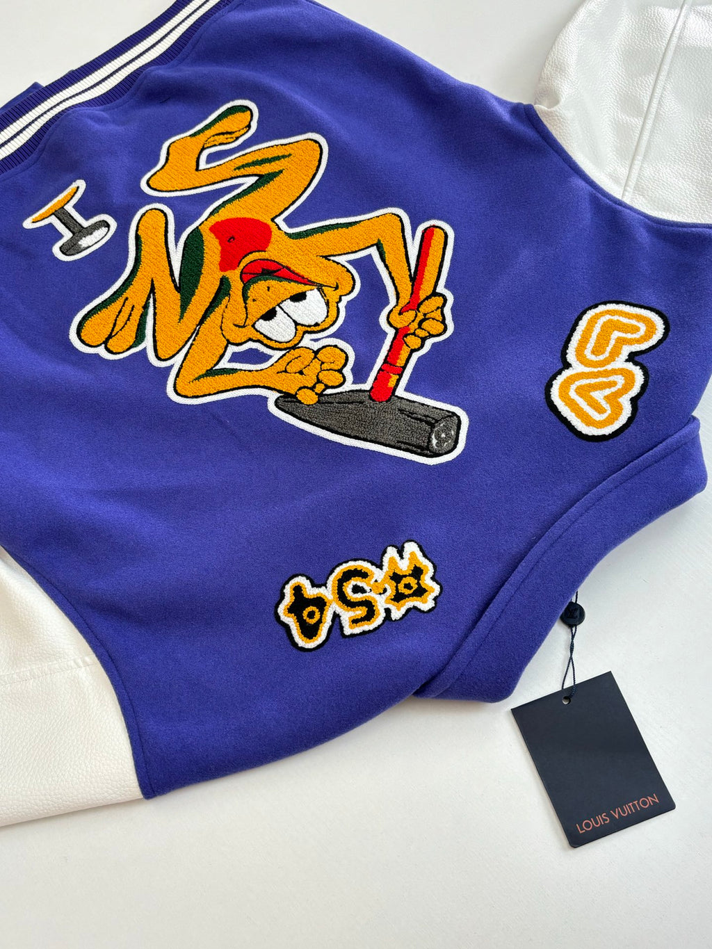 Blue varsity jacket with embroidered graffiti-style graphic and small side patches