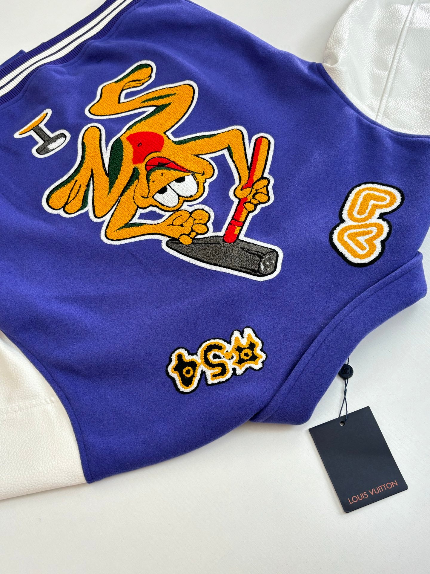Blue varsity jacket with embroidered graffiti-style graphic and small side patches