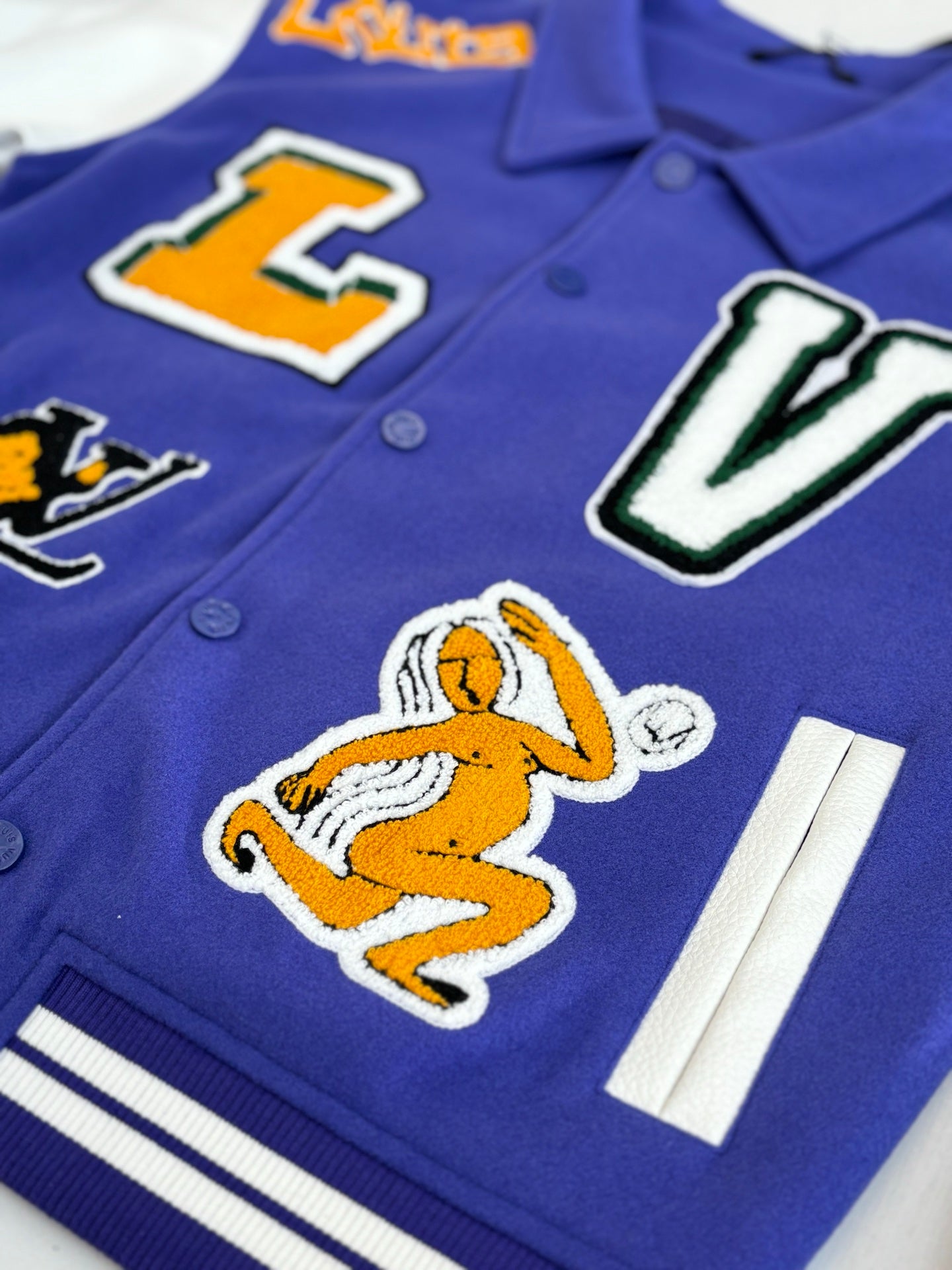 Blue varsity jacket close-up of embroidered cartoon and hand-held basketball graphic