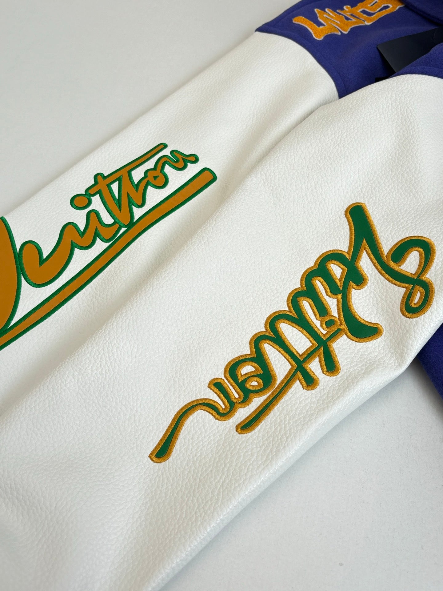 White long-sleeve sweatshirt sleeve with colorful embroidered text graphic