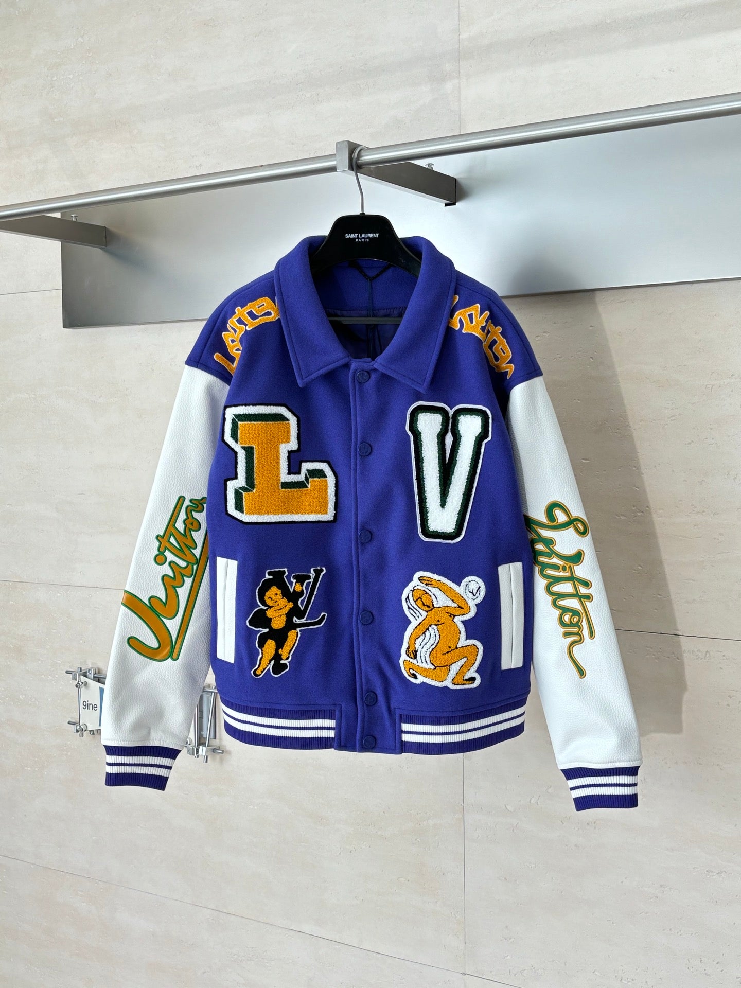 Blue varsity jacket with white sleeves, striped cuffs, and large front L and V patches
