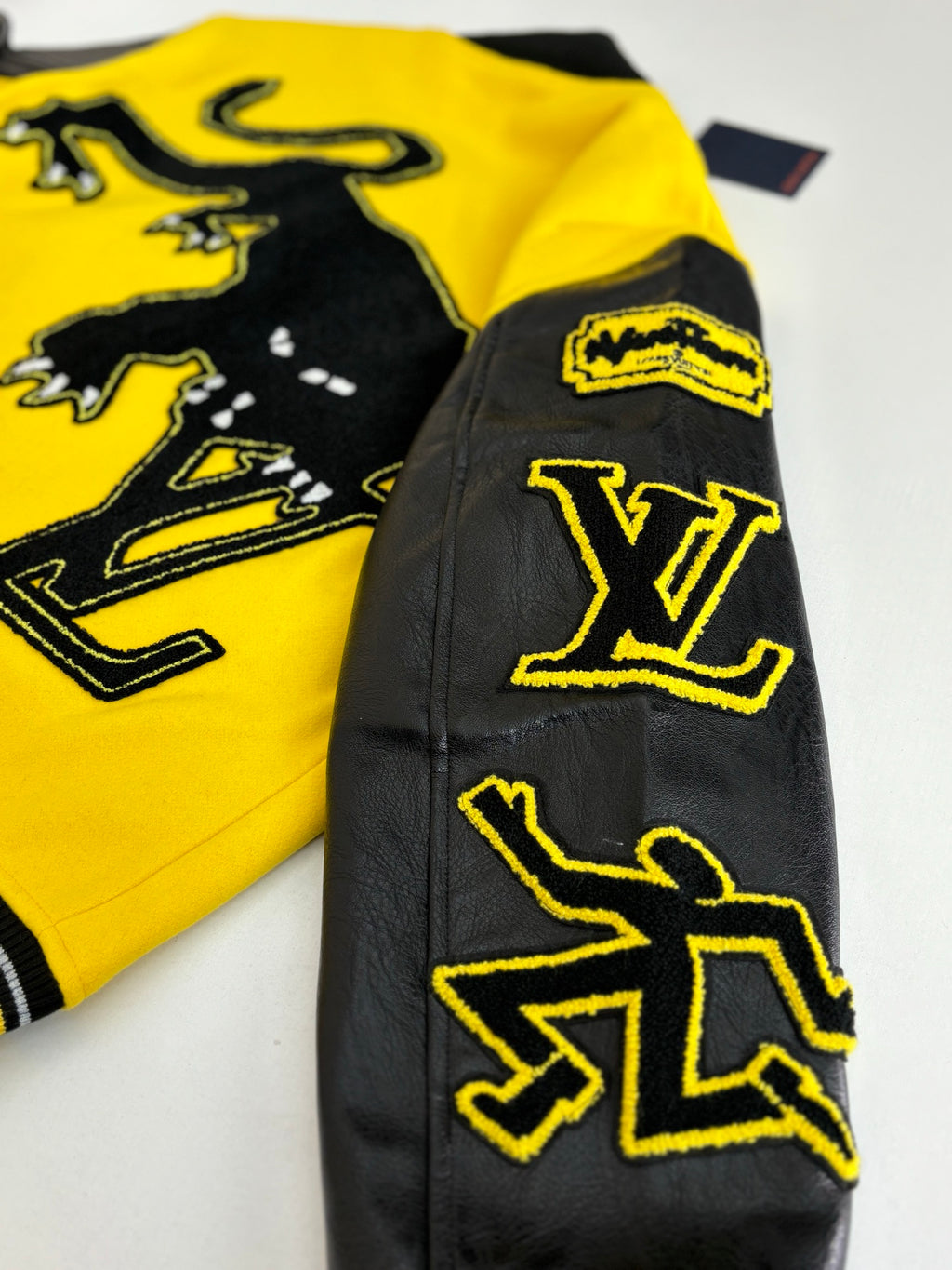 Louis Vuitton yellow and black varsity jacket sleeve detail with LV emblem on black leather