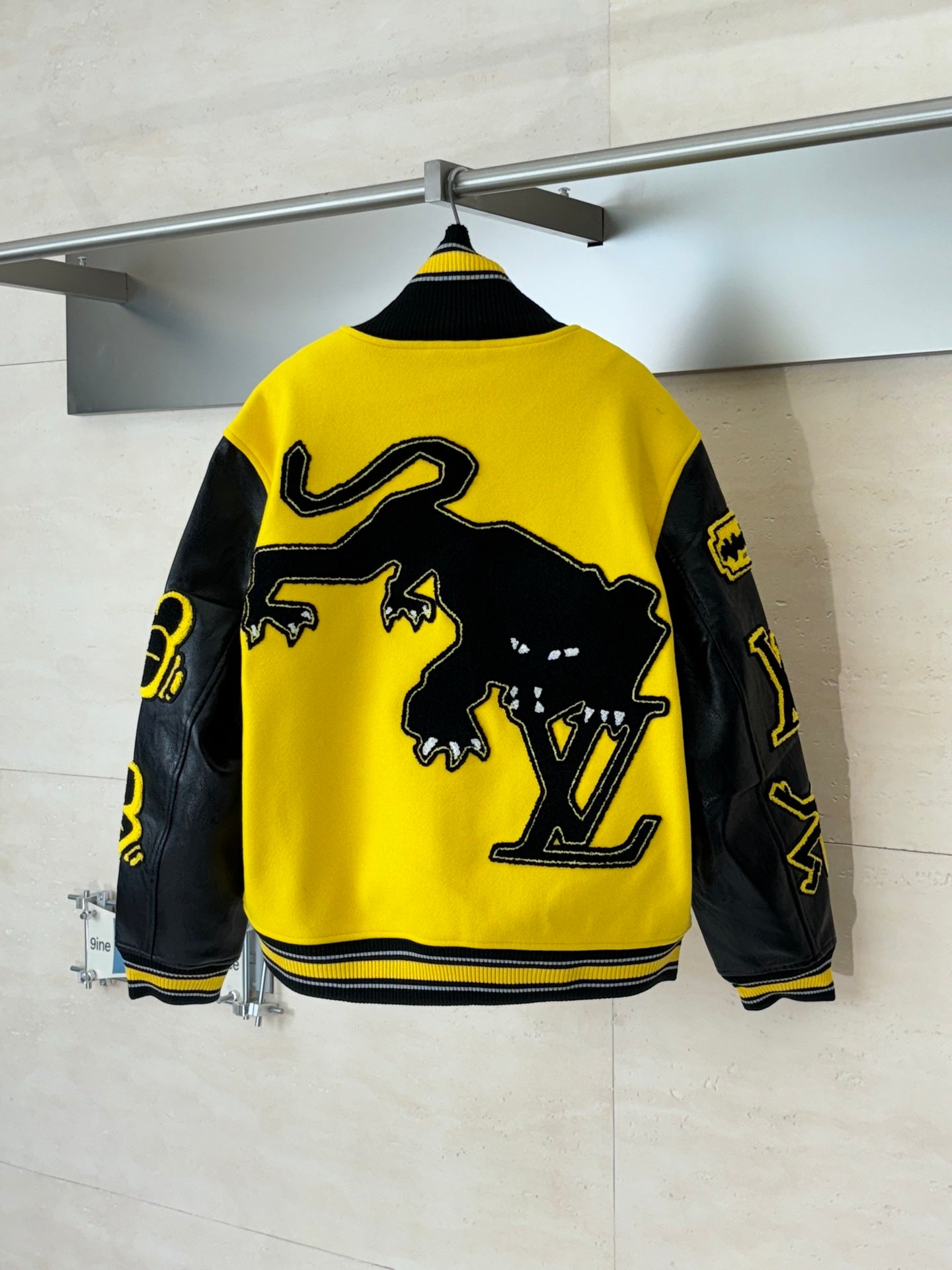Louis Vuitton yellow and black varsity jacket, back view with large LV logo graphic