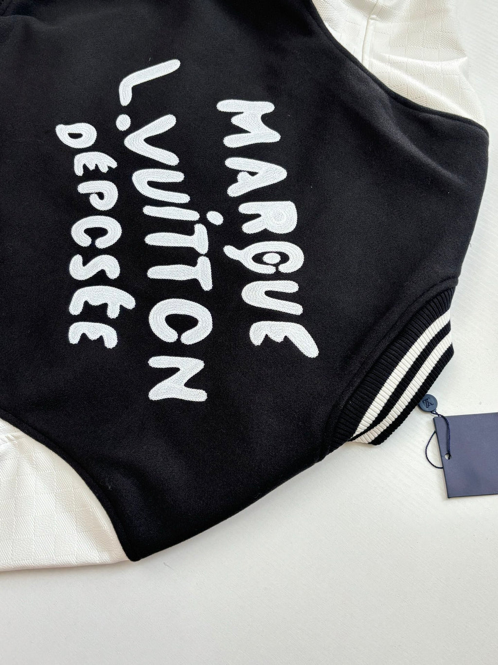 Louis Vuitton varsity jacket back, black with white vertical text graphic.