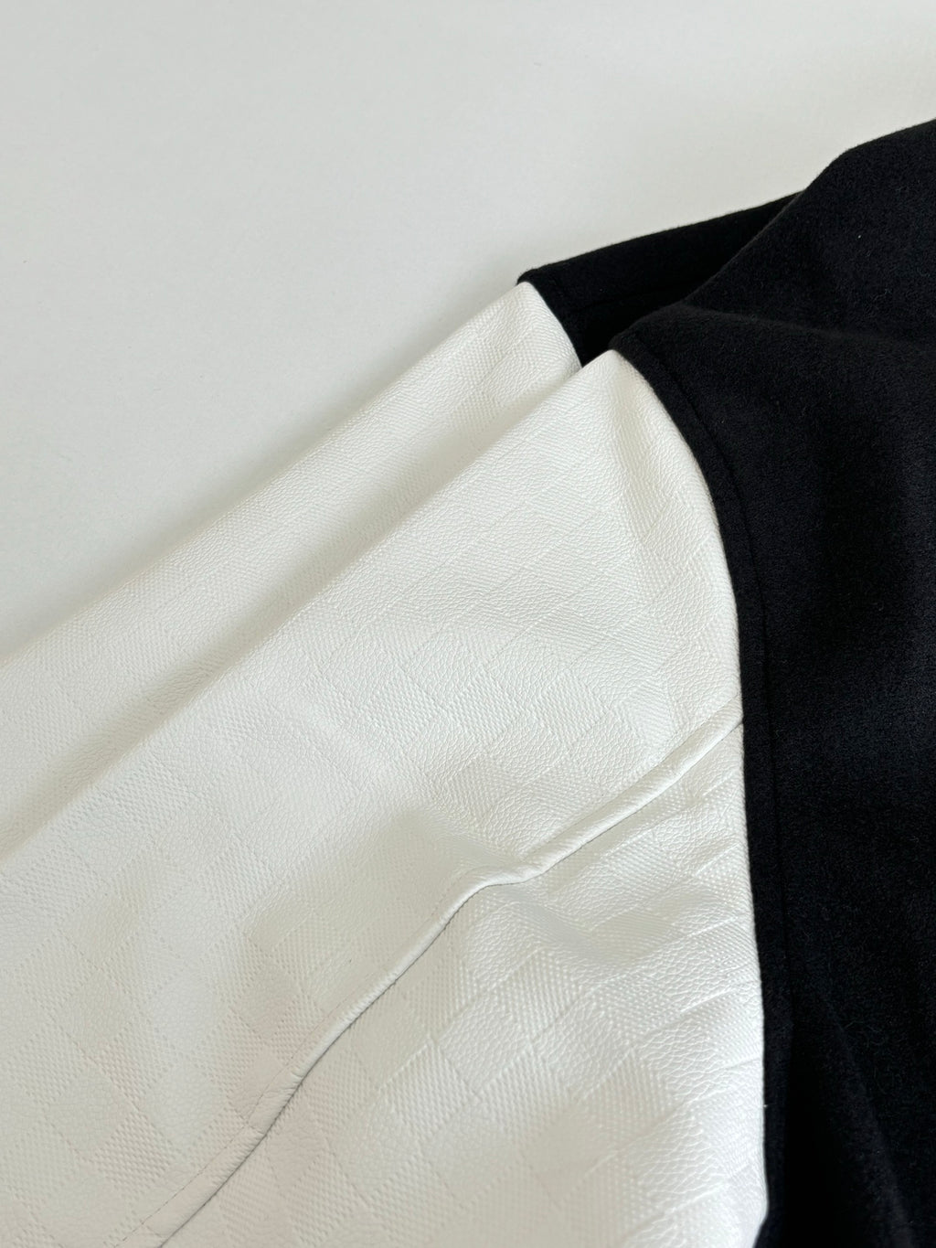 Louis Vuitton varsity jacket side view, black and white colorblock with ribbed edge.