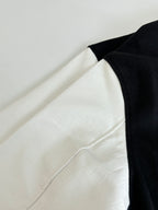 Louis Vuitton varsity jacket side view, black and white colorblock with ribbed edge.