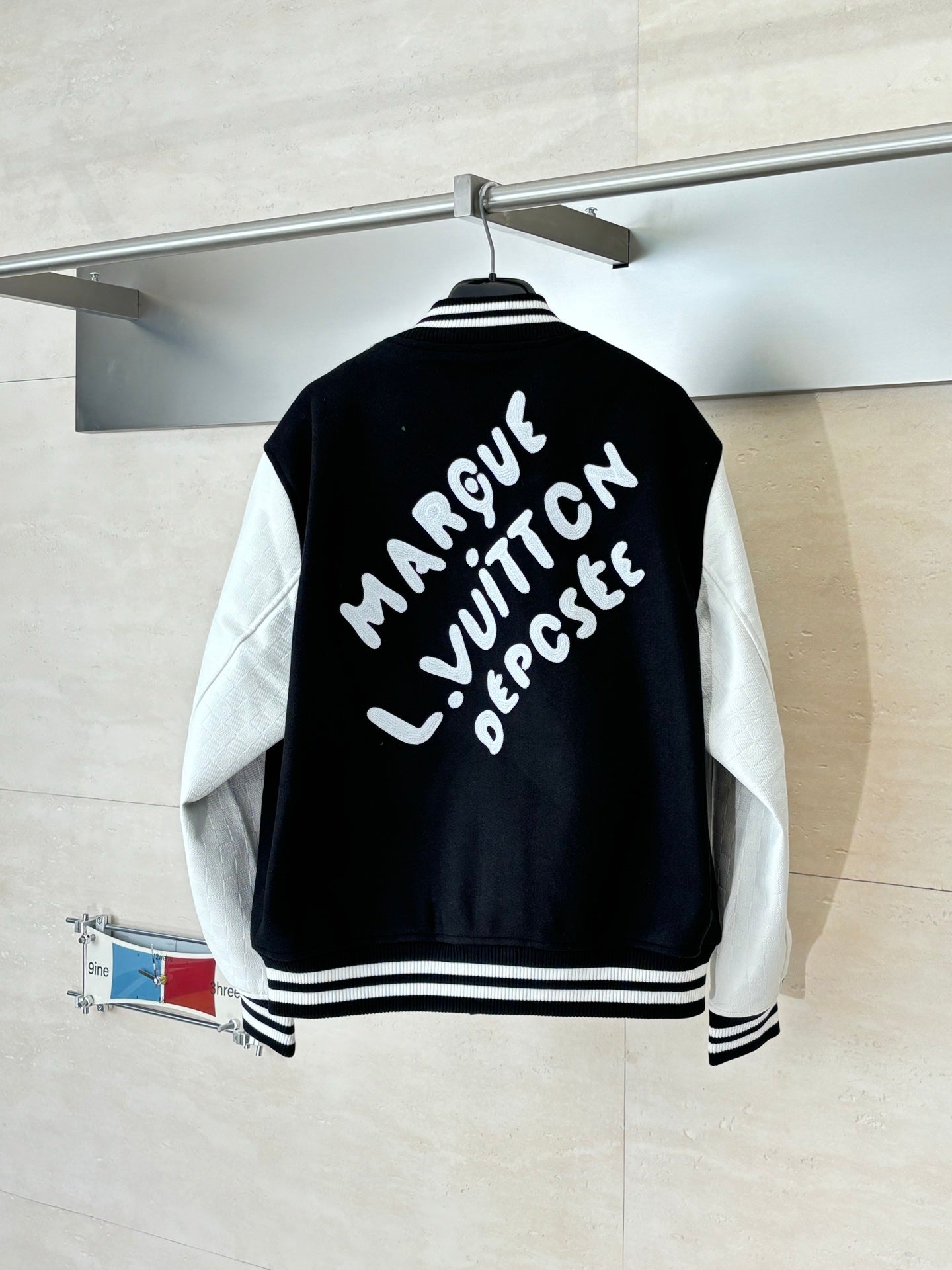 Louis Vuitton varsity jacket back, black with white lettering, striped ribbed hem.