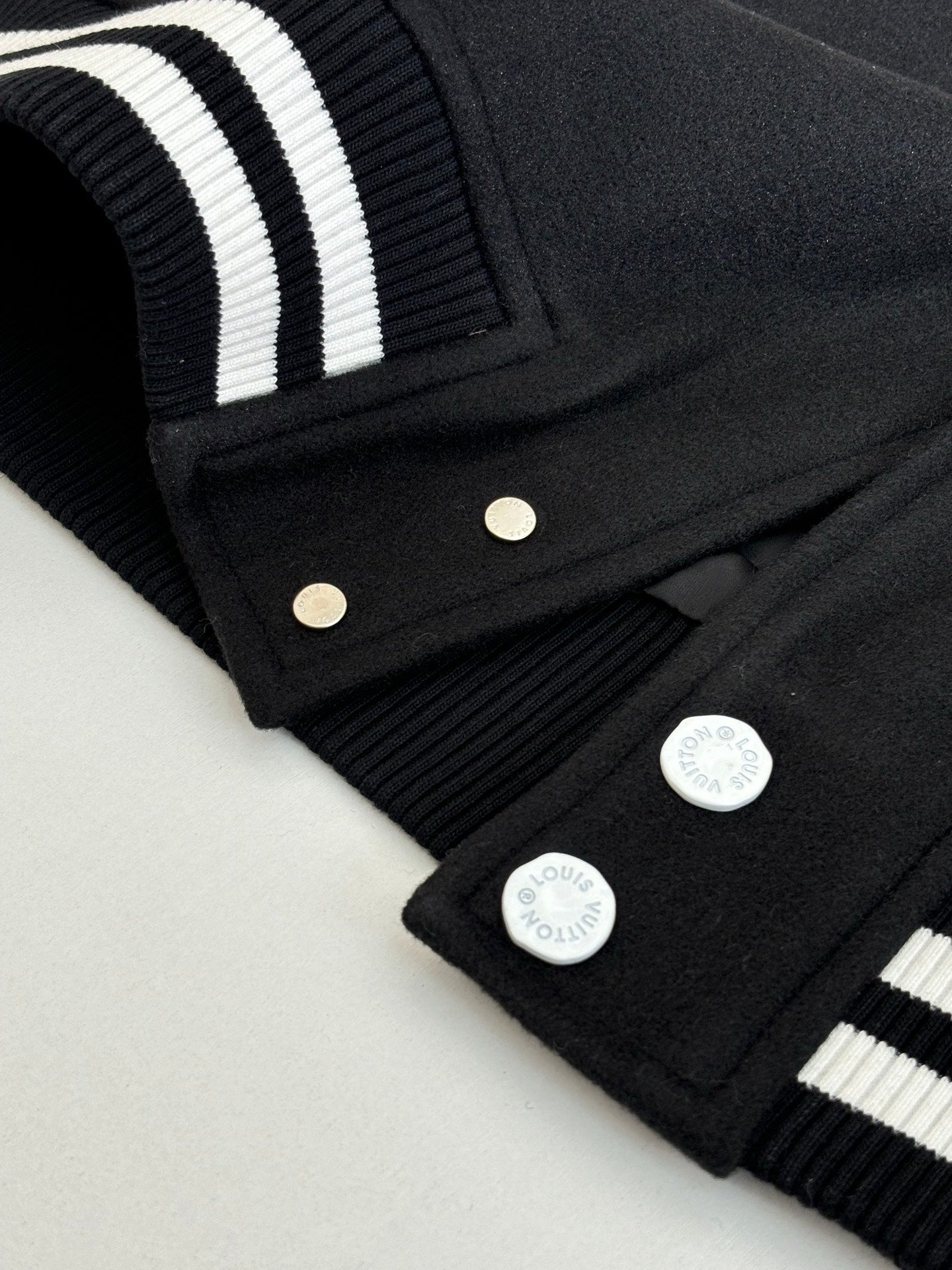 Louis Vuitton varsity jacket sleeve, black ribbed cuff with white stripes and snap placket.