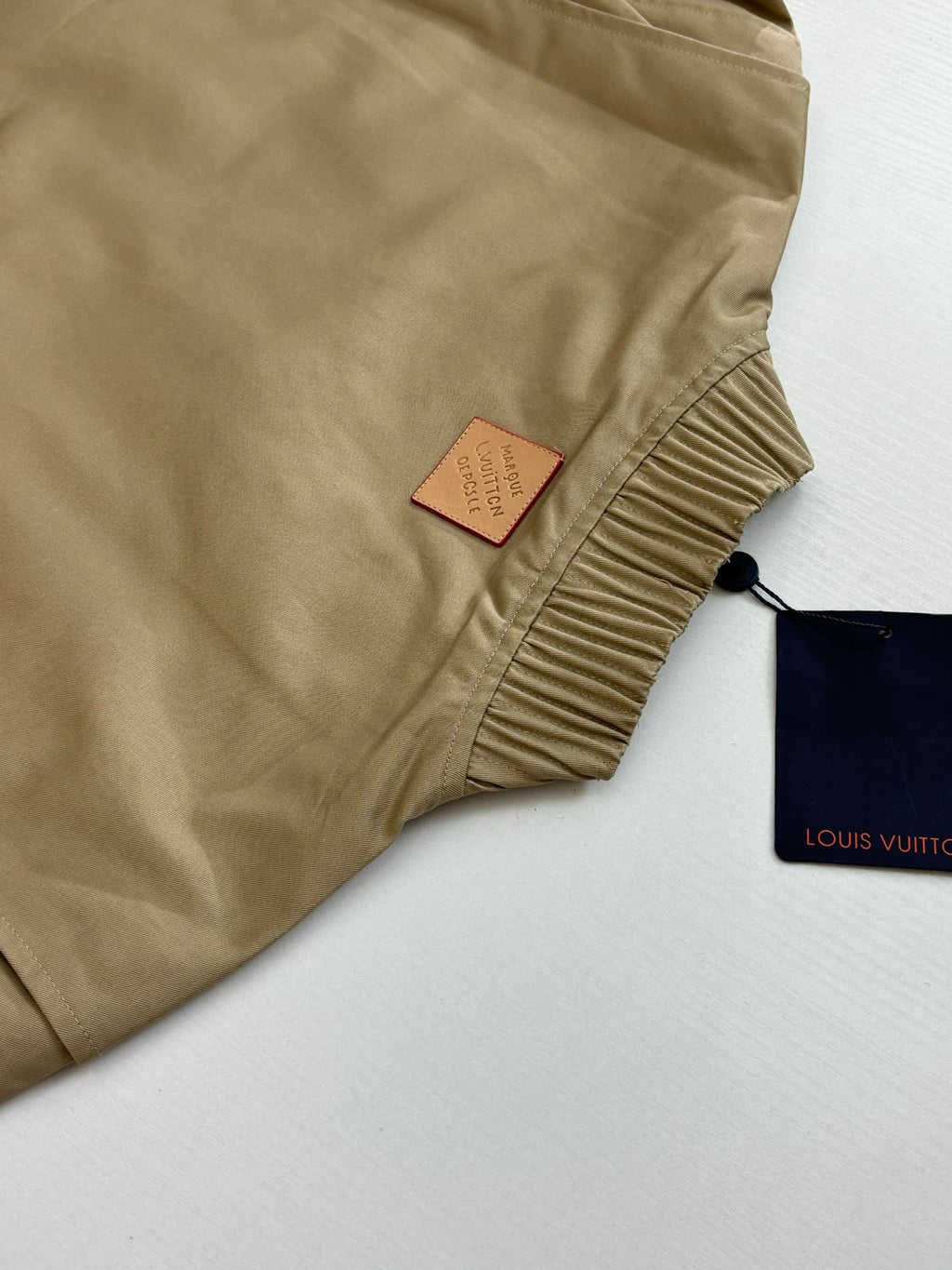Tan bomber jacket with Louis Vuitton hang tag and ribbed neck trim
