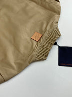 Tan bomber jacket with Louis Vuitton hang tag and ribbed neck trim