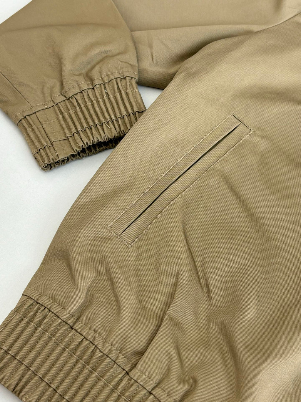 Tan bomber jacket sleeve and hem with ribbed cuffs and stitched side panel