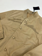 Tan bomber jacket close-up of embroidered front and snap button placket