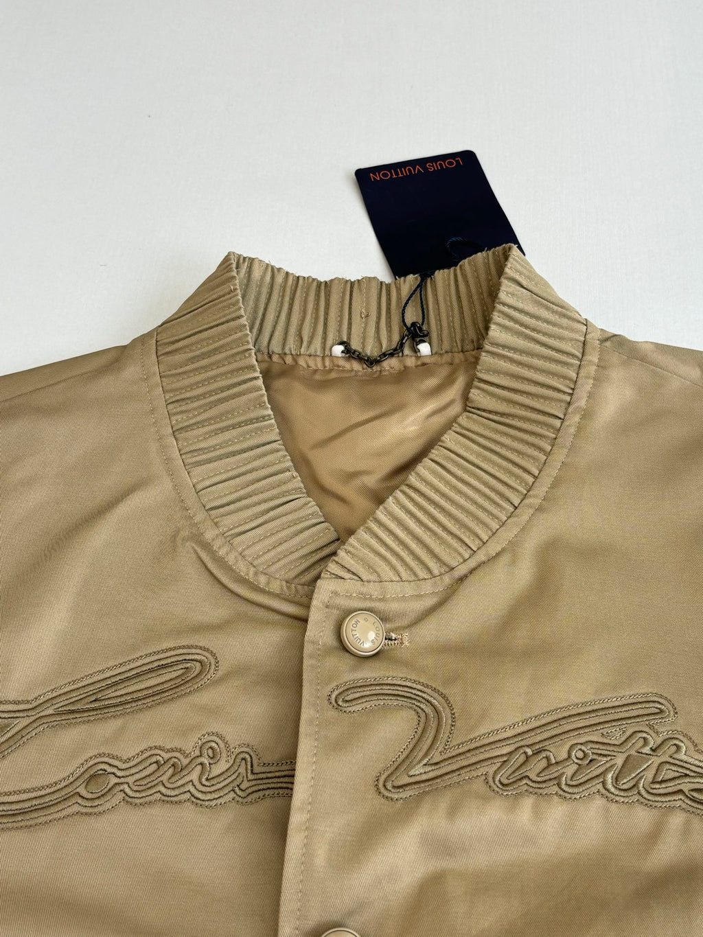 Tan bomber jacket collar close-up with ribbed trim and snap button placket
