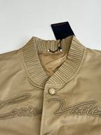 Tan bomber jacket collar close-up with ribbed trim and snap button placket