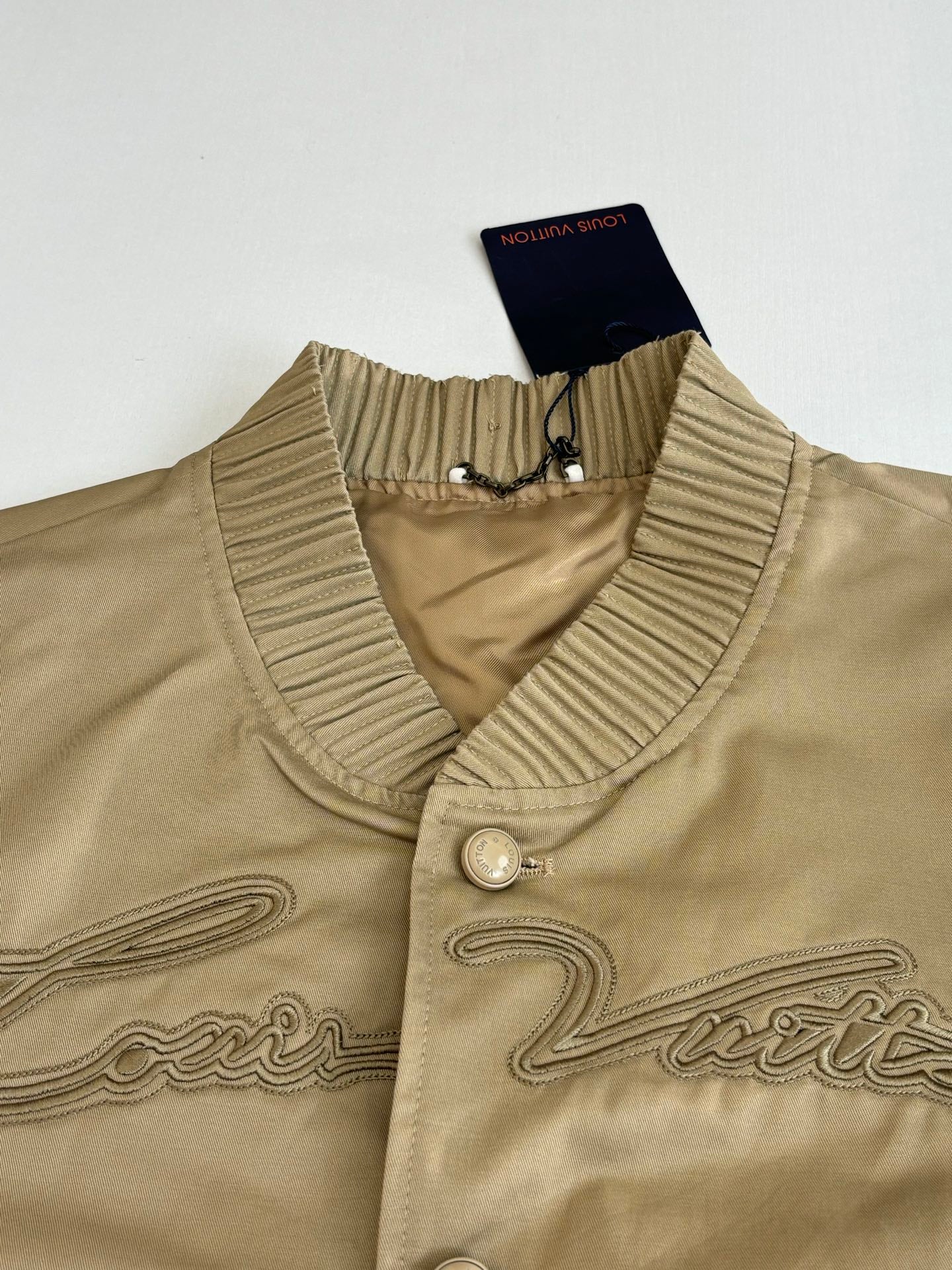 Tan bomber jacket collar close-up with ribbed trim and snap button placket