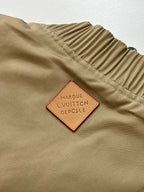 Tan bomber jacket label patch reading Louis Vuitton and dot symbol details