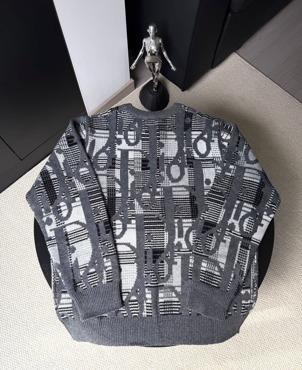 Gray knit sweater with long sleeves and abstract black-and-white logo pattern