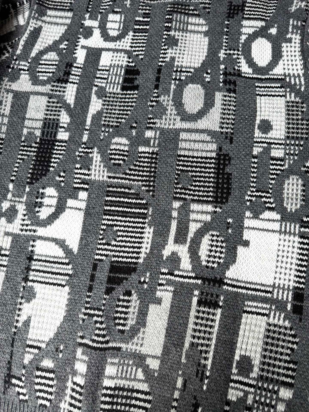 Close-up of gray knit sweater with dense black-and-white logo graphic pattern